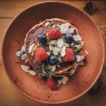 Shallow focus photography of pancake with strawberries and blueberries on top